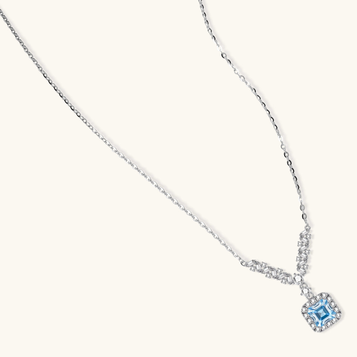 Sterling silver necklace with geometric crystal arrangement forming a V-shape and square blue moissanite centerpiece pendant