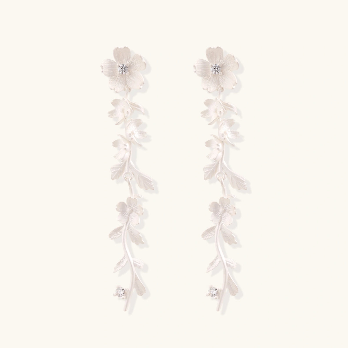 Long sterling silver drop earrings with delicate floral vine design and crystal accents on white background