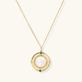 Gold pendant necklace with circular orbital design, iridescent mother-of-pearl center, and green zirconia accents