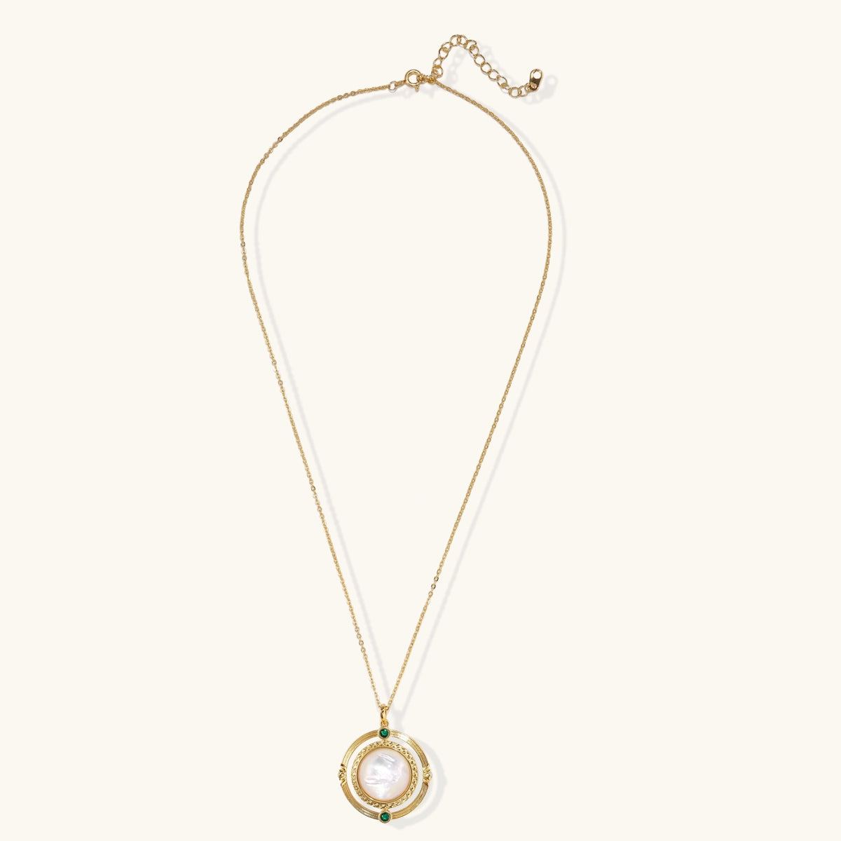Gold pendant necklace with circular orbital design, iridescent mother-of-pearl center, and green zirconia accents