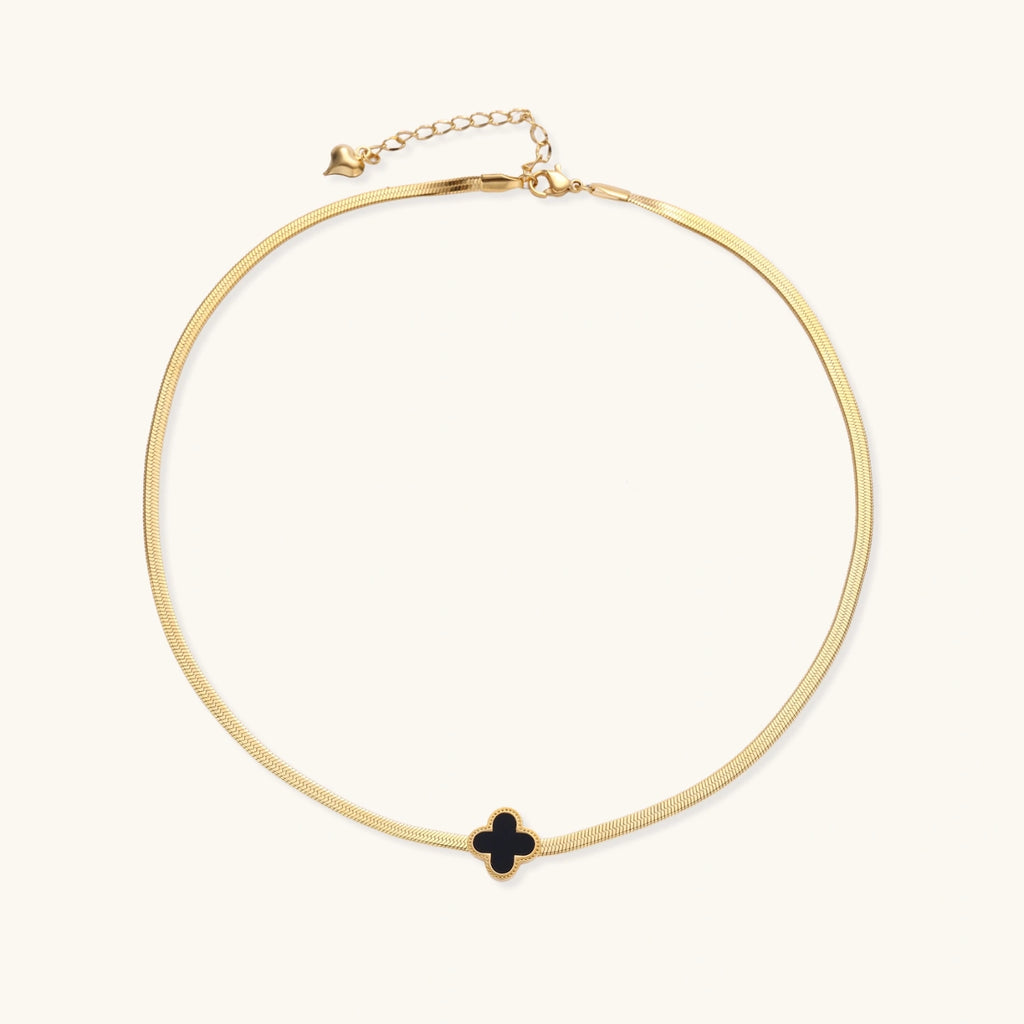 Dainty 18K gold-plated herringbone chain necklace with black enamel quatrefoil clover pendant on white background
