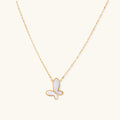 Gold-plated butterfly pendant with iridescent mother of pearl inlay on delicate chain against cream background.