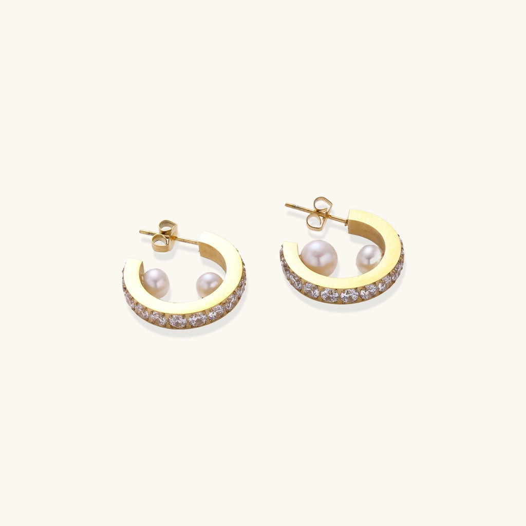 Gold pavé hoop earrings with two freshwater pearls nestled inside the curved design, featuring crystal-studded outer edge.