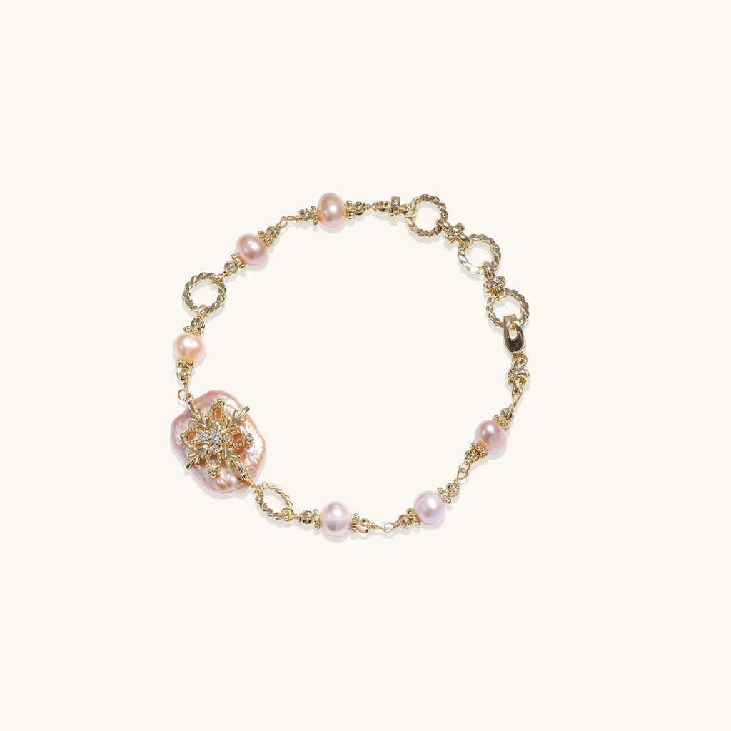 Gold-plated bracelet with pink baroque pearl centerpiece, floral connector, and freshwater pearls